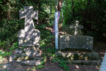 Cross monument on graves of an abandoned old cemetery. Graveyard in memorial forest