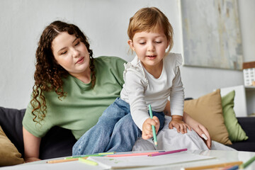A mother watches her daughter joyfully draw and express her creativity at home.
