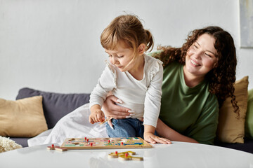 A loving mother enjoys playful moments with her daughter while they engage in an activity together.