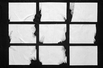 White torn posters on black background.