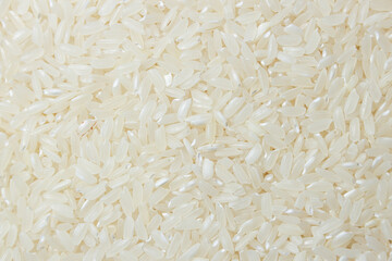 Dry Uncooked White Rice Background - Top View, Flat Lay. Scattered Raw Long Grain Rice. Asian Cuisine and Culture. Healthy Eating Ingredients. Diet Food