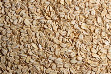 Uncooked Oat Flakes background - Top View, Flat Lay. Scattered Dry and Raw Oat Flakes. Healthy Breakfast and Diet Eating Ingredients
