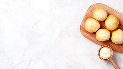 Delightful cream puffs arranged on a rustic wooden board accompanied by creamy white chocolate on a softly lit table