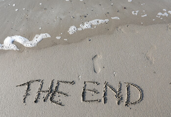 text with the words THE END carved on the sandy beach and the sea wave about to erase it