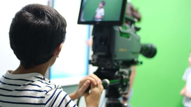 oy learns to use video camera. Filmmaking, education, technology, green screen, studio, learning, childhood.