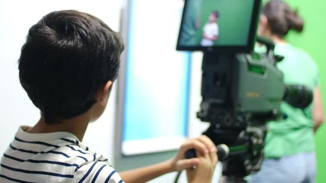 oy learns to use video camera. Filmmaking, education, technology, green screen, studio, learning, childhood.