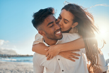 Obraz premium Piggyback, kiss and couple by beach on vacation, getaway or holiday with travel together. Happy, love and interracial man and woman with playful romance by ocean or sea on date on weekend trip.
