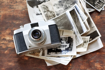 Wooden table, vintage and camera with retro photographs on black and white. Digital, old school and...