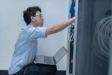 Computer engineer is setting up network in server room,Systems Maintenance Technician,Male engineer working in server room at modern data center