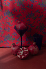 Still life with pomegranates on red vintage background with blue glasses lifestyle fall composition