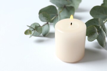 Beautiful composition with burning wax candles and eucalyptus on the tablе