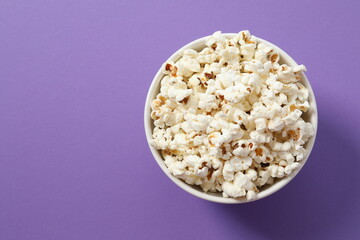 Delicious popcorn in a bowl on a color background