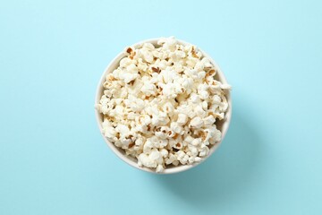 Delicious popcorn in a bowl on a color background