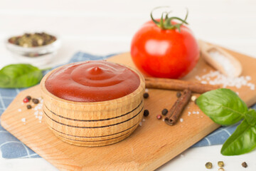 Delicious ketchup with spices and tomatoes on wooden table