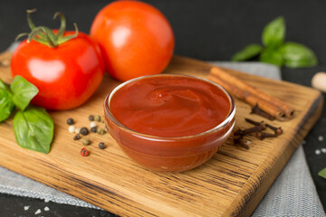 Delicious ketchup with spices and tomatoes on wooden table