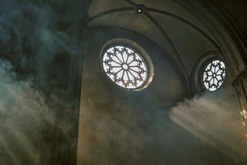 Low angle shot of amazing church walls with beautiful round windows, divine light fog in church air