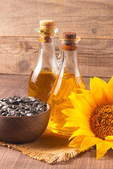 Closeup photo of sunflower oil with seeds on wooden background. Bio and organic product concept.