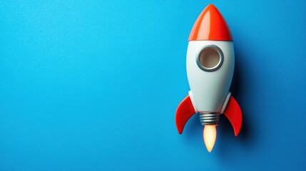 A red and white toy rocket with a flame taking off against a blue background.