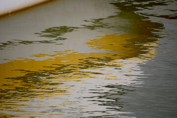 Reflection of a white and yellow boat on a smooth water surface