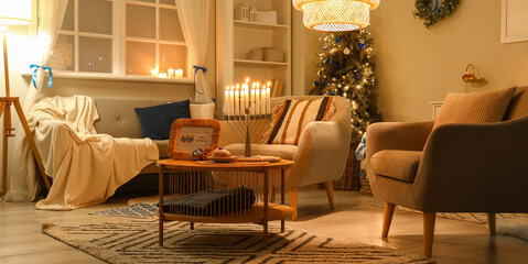 Interior of living room decorated for Hannukah with armchairs and table at night