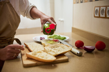 Chef adding olive oil to fresh bread in kitchen setting