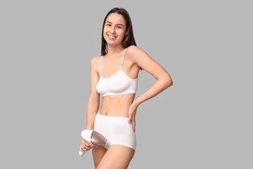 Fototapeta premium Happy young woman with modern photoepilator on grey background