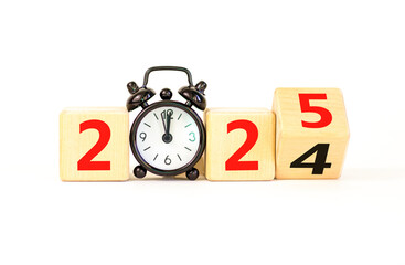 Business concept of 2025 new year symbol. Beautiful turned wooden cube and changed number 2024 to 2025. Beautiful white table background, copy space. Alarm clock. Business 2025 happy new year concept.