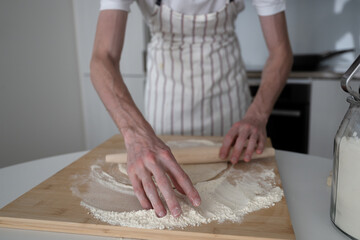 man using rolling pin for yeast dough in the domestic kitchen