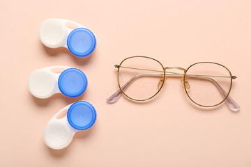 Stylish eyeglasses with containers for contact lenses on beige background