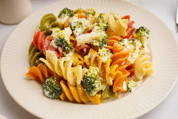 Delicious fusilli pasta with broccoli and cheese in plate on light background, closeup