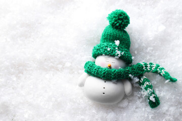 Cute decorative snowman on artificial snow, top view. Space for text