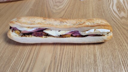 Sandwich de pain montagnard,  fromage, pommes de terre, bœuf, posé sur table en bois