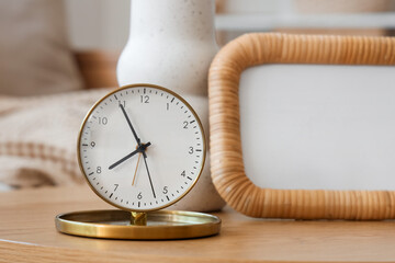 Golden alarm clock with vase and frame on coffee table in room. Closeup