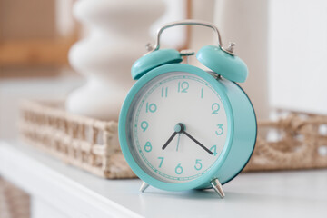 Turquoise alarm clock with decor on shelf in room. Closeup