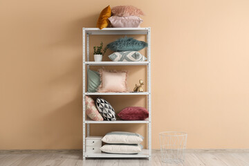 Shelving unit with pillows and houseplants near beige wall in living room
