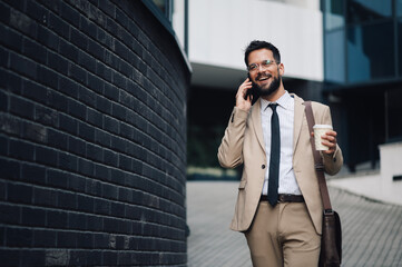 Businessman walking and talking on the phone while holding coffee