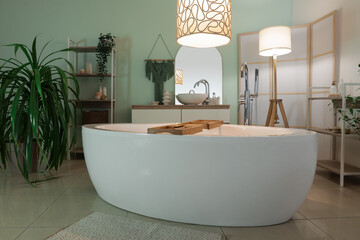 Interior of bathroom with bathtub, plants and glowing lamps in evening