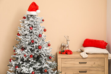 Decorated Christmas tree with gifts and chest of drawers with deer, gifts, cushion and plaid in interior of living room