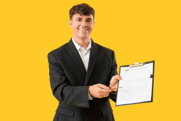 Male real estate agent with house rental agreement on yellow background