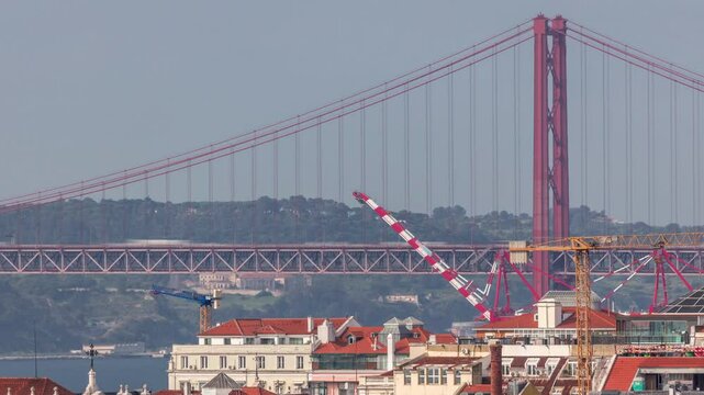 Aerial view towards Barrio Alto and 25th of April Bridge timelapse, Lisbon, Portugal. Colorful historic buildings with cranes in cargo port