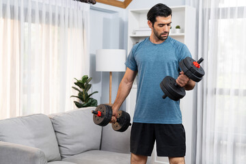 Athletic body and active sporty man lifting dumbbell weight for effective targeting muscle gain at gaiety home as concept of healthy fit body home workout lifestyle.