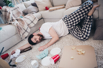 Full length photo of handsome young guy lying floor sleeping dressed nightwear wake up after party...