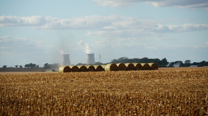 Fototapeta premium Farm Harvest With Power Plant Smoke Stacks In Background
