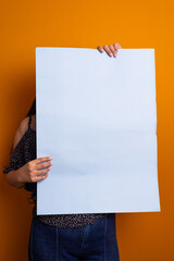 Woman holding a blank poster in front of her face.