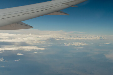 Obraz premium Looking out an airplane window at clouds and farmland under the wing of my airplane. 