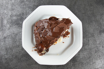 Piece of homemade cake with chocolate frosting on a gray background