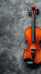 Naklejka premium A beautifully crafted wooden violin rests against a textured gray background