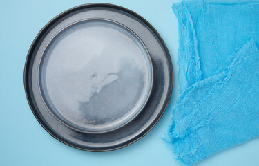Round ceramic empty blue plates and blue kitchen towel, top view