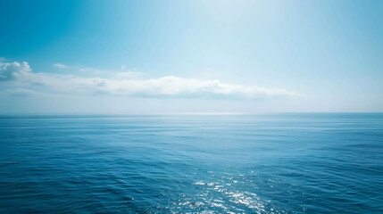 Obraz premium The deep blue sea stretches out to the horizon, meeting the bright blue sky above. The water is calm and still, reflecting the light of the sun.