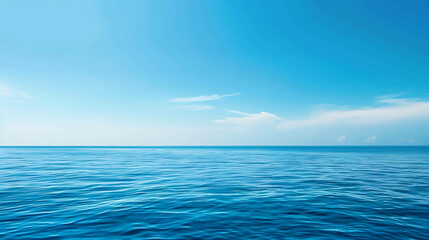 Fototapeta premium Deep blue ocean with a clear blue sky and white clouds. The water is calm and still, with small waves rippling on the surface.